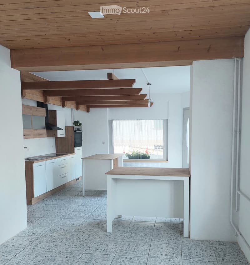 Modern kitchen with white cabinets, wooden accents, central island, and built-in appliances.