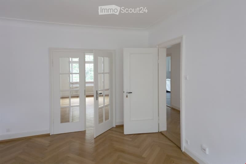 3 doors, wooden floor, white walls, white radiators, visible rooms behind doors