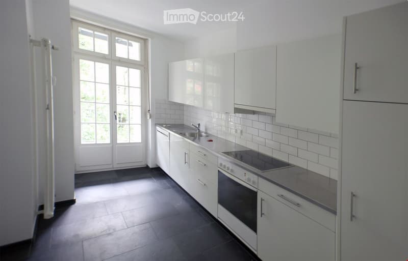 white cabinetry, tiled backsplash, modern appliances, dark floors, glass doors, sink with faucet, white walls
