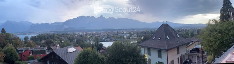 View of a town with houses, trees, and mountains in the background.