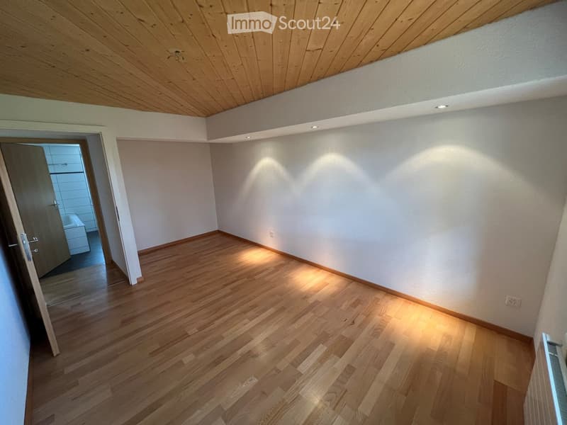 empty room, wooden floor, white walls, wooden ceiling, two doors, one leading to a bathroom