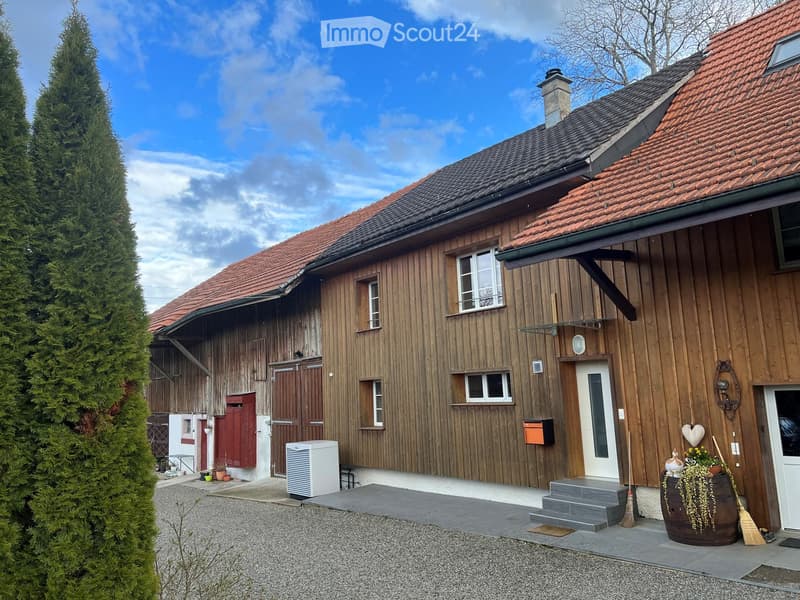 3 story house, brown wooden exterior, red roofs, multiple windows, chimney, gravel driveway, air conditioning unit, mailbox, potted plants