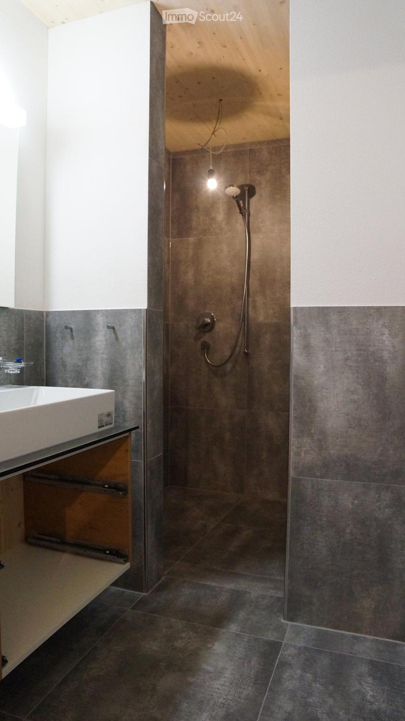 Bathroom with shower, sink, and wooden cabinet