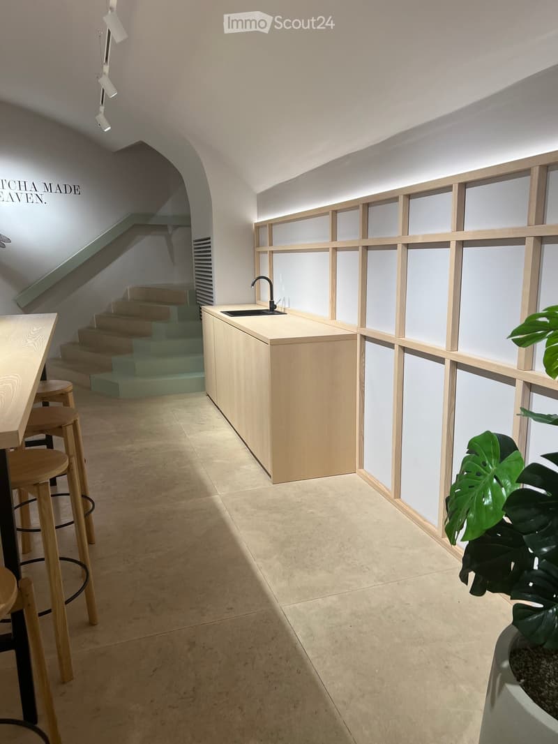 kitchen area with wooden counter, sink, faucet, wooden stools, tiled floor, wooden wall panels, staircase
