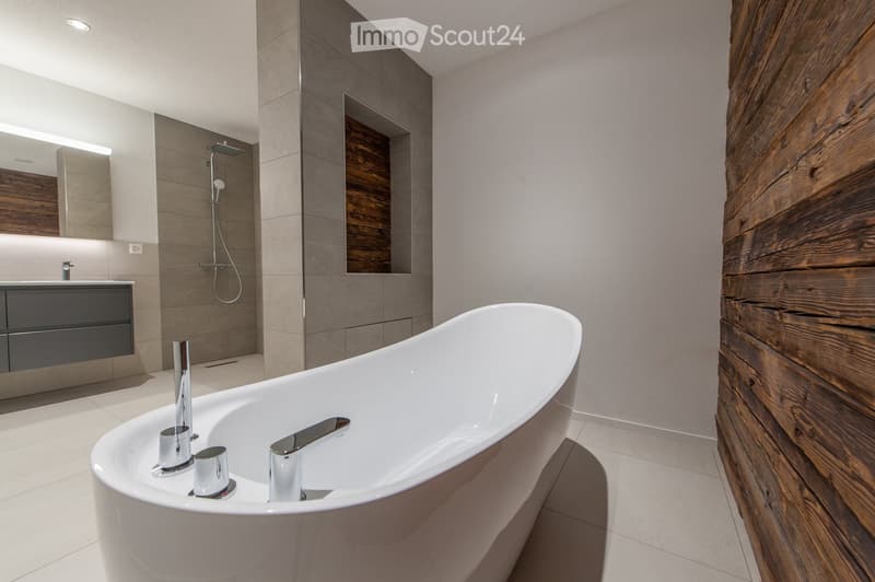 Modern bathroom with a freestanding bathtub, sleek chrome faucets, a large mirror, and a contemporary vanity unit.