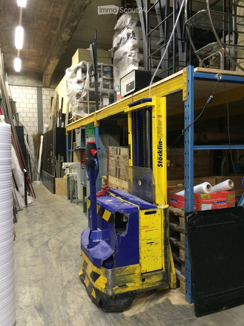 A warehouse or storage area with a forklift, shelves, and various boxes and tools.