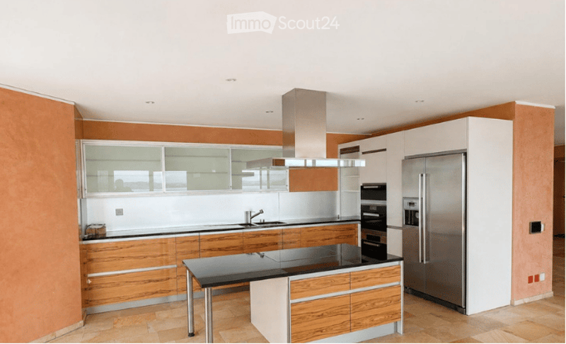 Modern kitchen with wooden cabinets, stainless steel appliances, island, and a sleek hood.