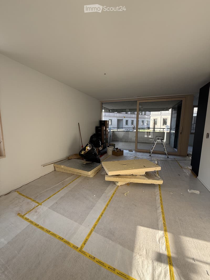 Empty room with unfinished flooring and walls, featuring a large glass sliding door leading to a balcony area.