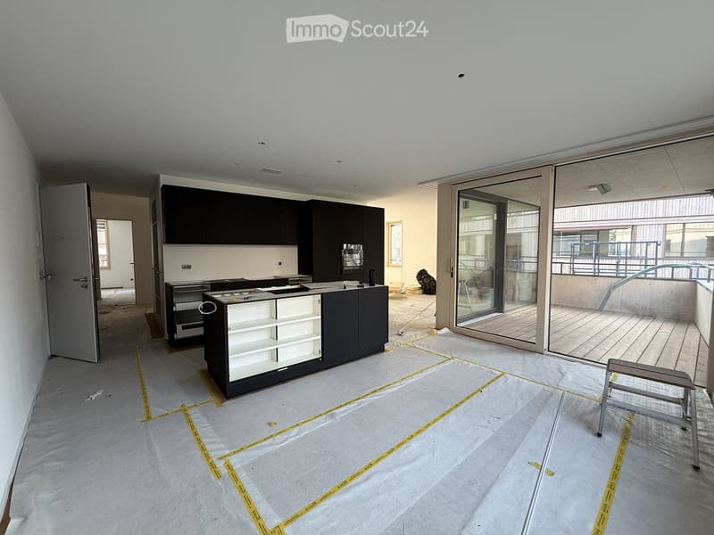 Modern kitchen with black cabinets, white countertop, and a large sliding glass door leading to a balcony.