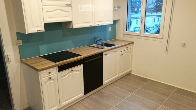 modern kitchen with wooden counter, white cabinets, blue backsplash, dishwasher, electric stove