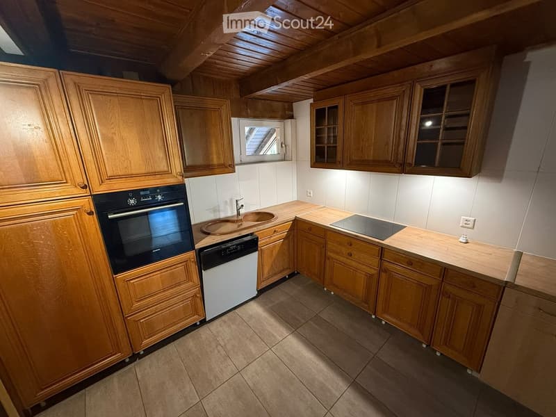 Kitchen with wooden cabinets, stainless steel oven, dishwasher, sink, and countertop.