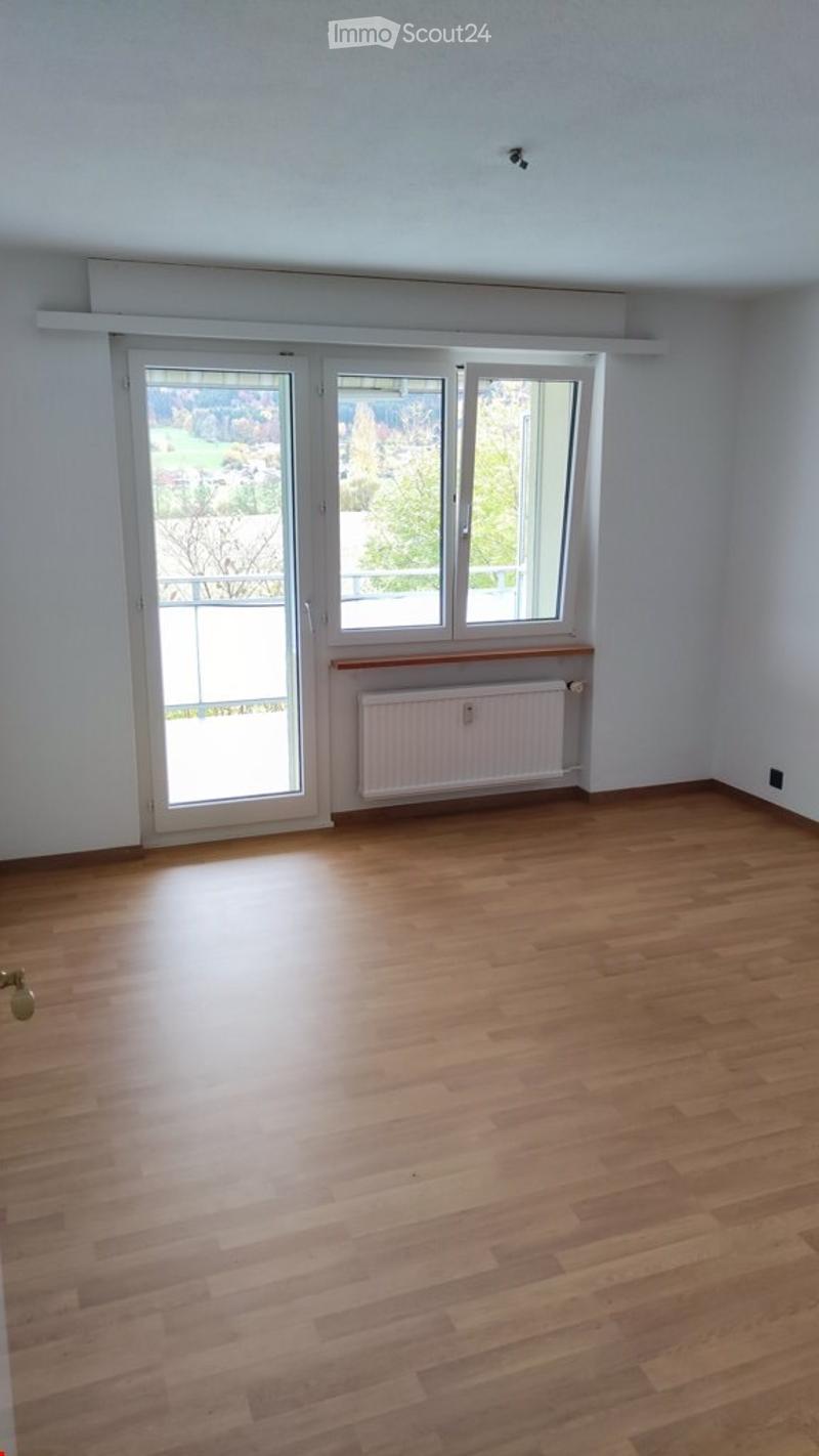Empty room with wooden flooring, white walls, large windows, and a radiator. No furniture or equipment present.