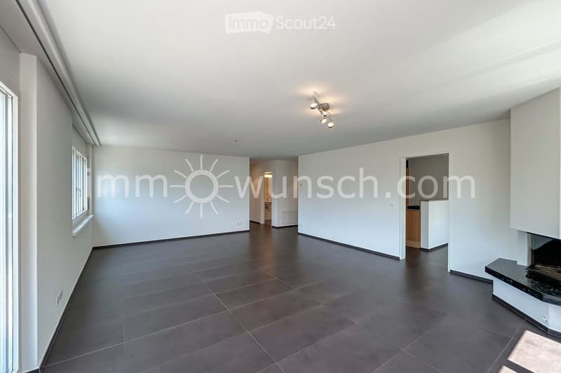 Empty room with dark tiled floor, white walls, and large windows. No furniture or equipment visible.