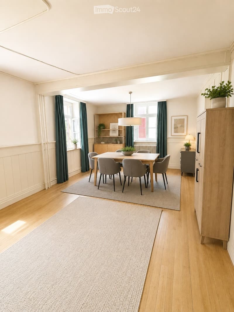 Bright dining area with wooden flooring, a central dining table surrounded by six chairs, a modern pendant light, and a built-in wooden cabinet with shelves and a lamp on top. Two rugs are placed on the floor, and there are potted plants and framed artwor