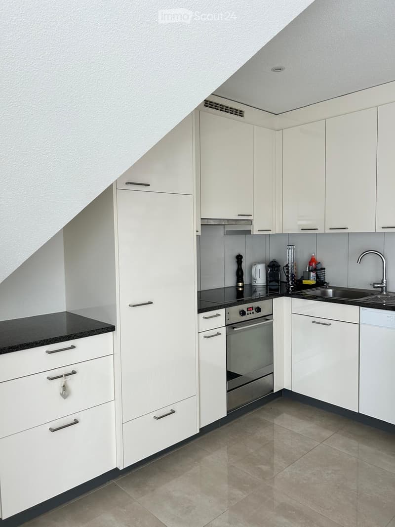 Modern kitchen with white cabinets, stainless steel appliances, and a black countertop.