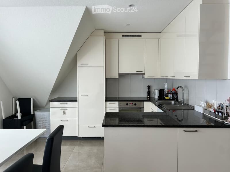 Modern kitchen with white cabinets, black countertops, stainless steel sink, and various appliances.