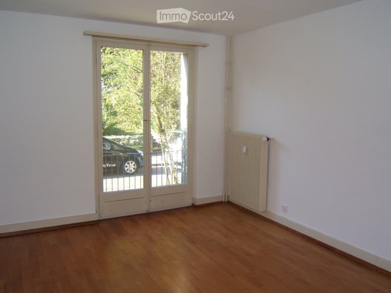 Empty room with wooden flooring, white walls, and a large sliding glass door leading to an outdoor area.