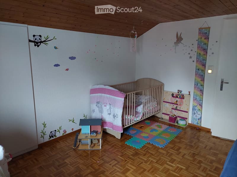 Child's bedroom with wooden crib, toy house, play mat, and height chart on the wall.