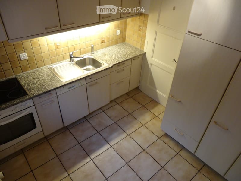 Compact kitchen with granite countertop, sink, oven, dishwasher, and white cabinets.