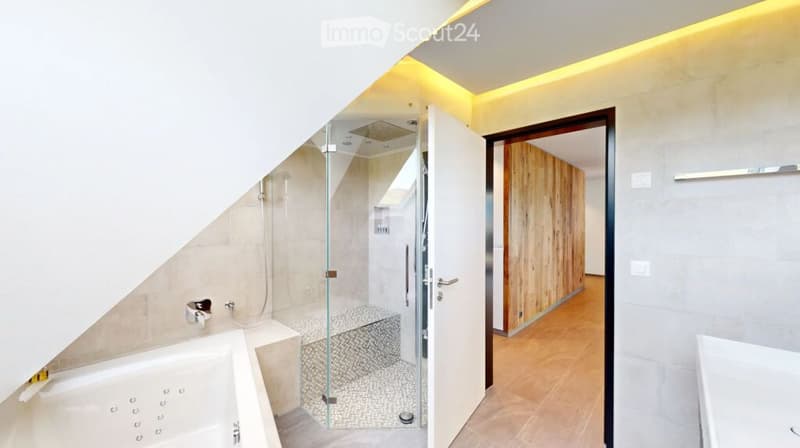 Modern bathroom with a bathtub, glass-enclosed shower, and sleek fixtures. The space features warm lighting and a contemporary design.