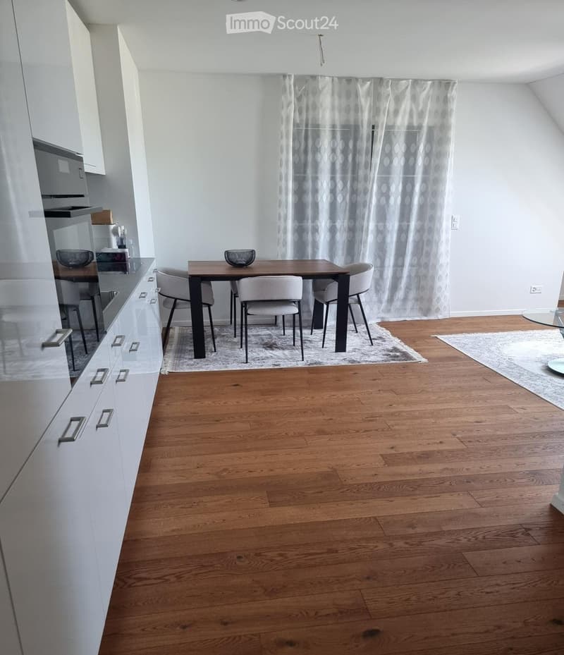 Modern dining area with wooden floor, white cabinets, a dining table with four chairs, and a bowl on the table.