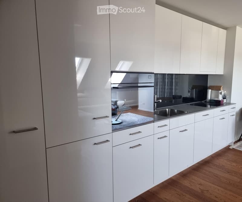 Modern kitchen with white cabinets, stainless steel sink, and a visible oven in the background.