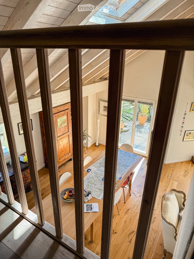 A well-lit room with wooden floors, a dining table with chairs, a sofa, a cabinet, and a view to a balcony area with outdoor furniture.