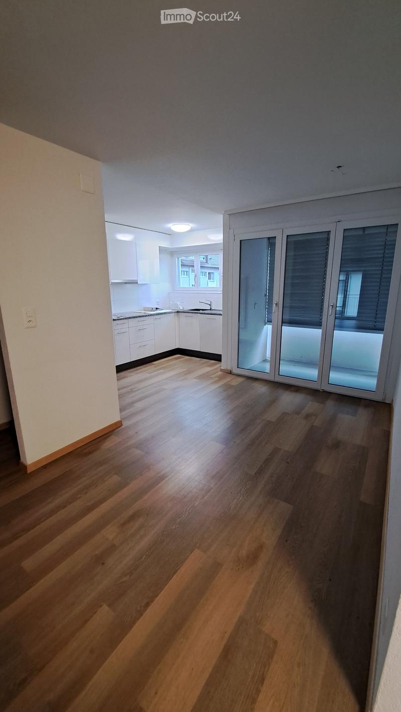 Empty room with wooden flooring, white cabinets, and a sliding glass door leading to a balcony.