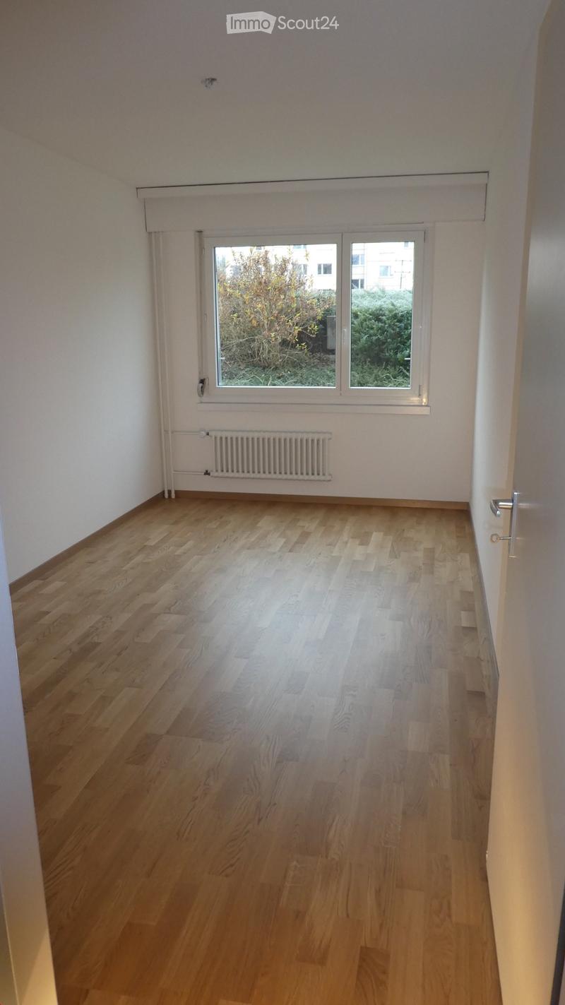 Empty room, wooden floors, white walls, window with white frame, white radiator, no furniture
