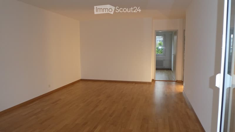 empty room with hardwood floors, sliding door, windows, white walls