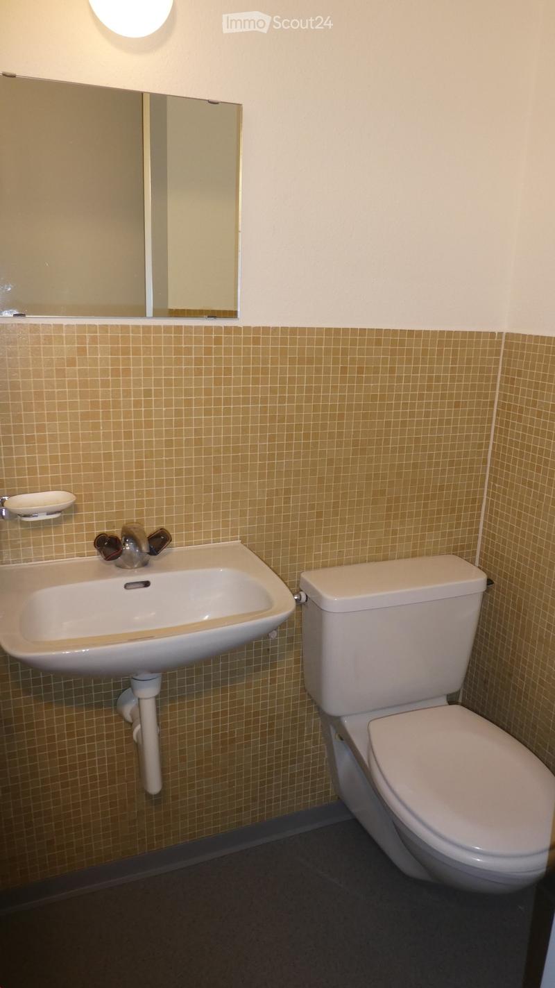 White toilet, sink, mirror on wall, tiled floor, no window, clean and functional