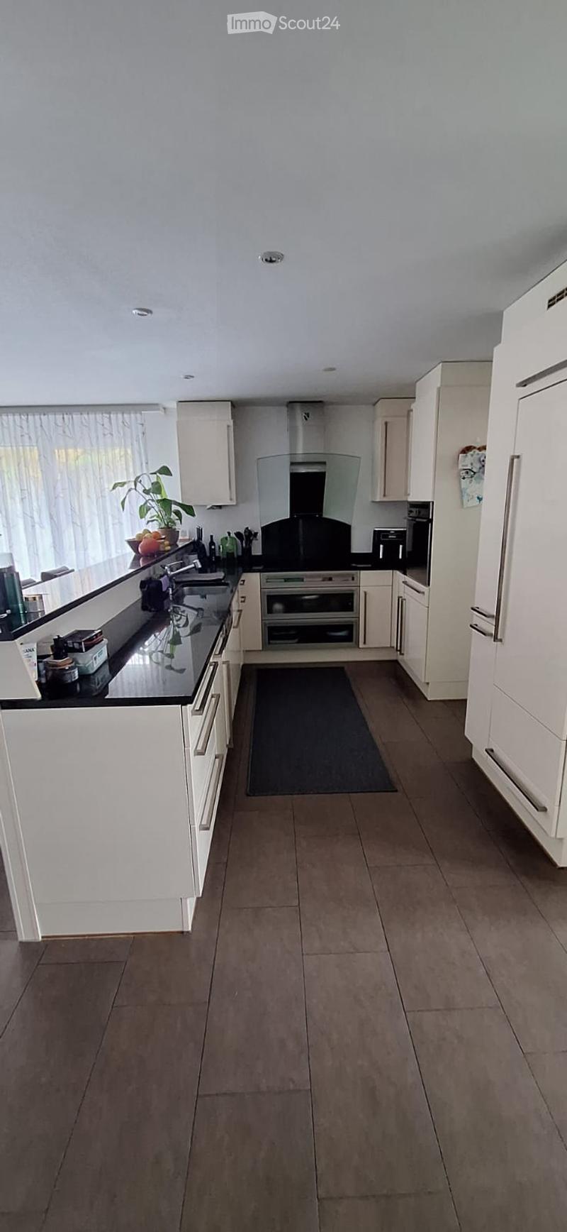 Modern kitchen with white cabinets, black countertops, stainless steel appliances, and a central island with a sink and faucet.