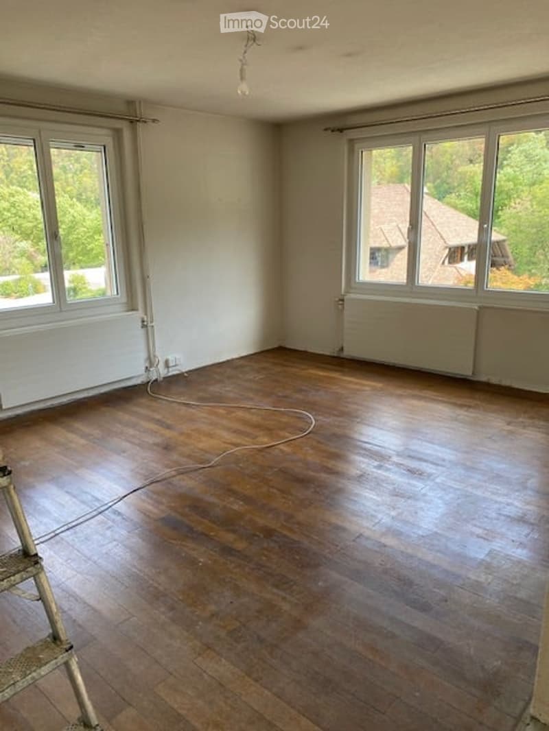 Empty room with wooden flooring, large windows, and radiators. No furniture or equipment present.