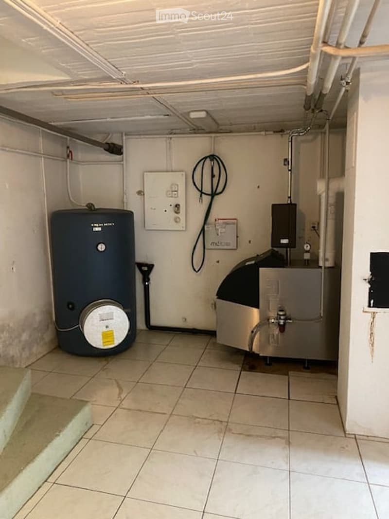 Utility room with tiled floor, exposed pipes, water heater, and electrical panel.