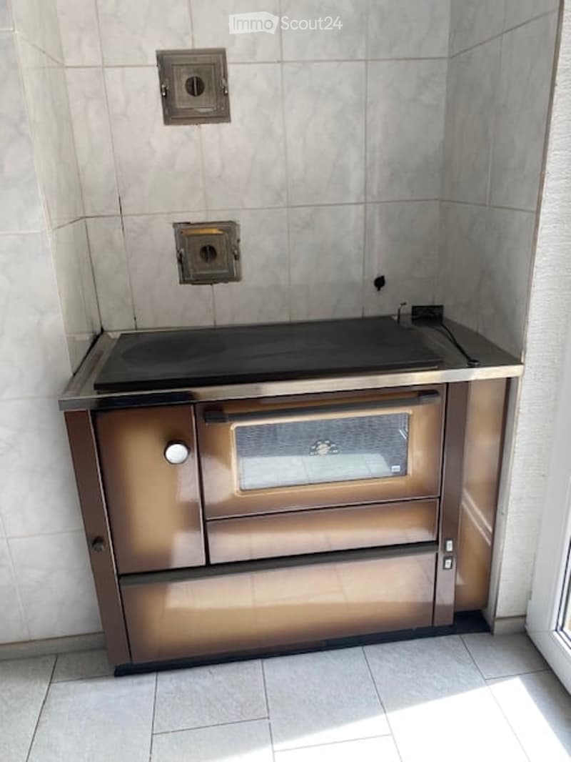Modern kitchen with a built-in stove and oven, featuring sleek stainless steel surfaces and tiled walls.