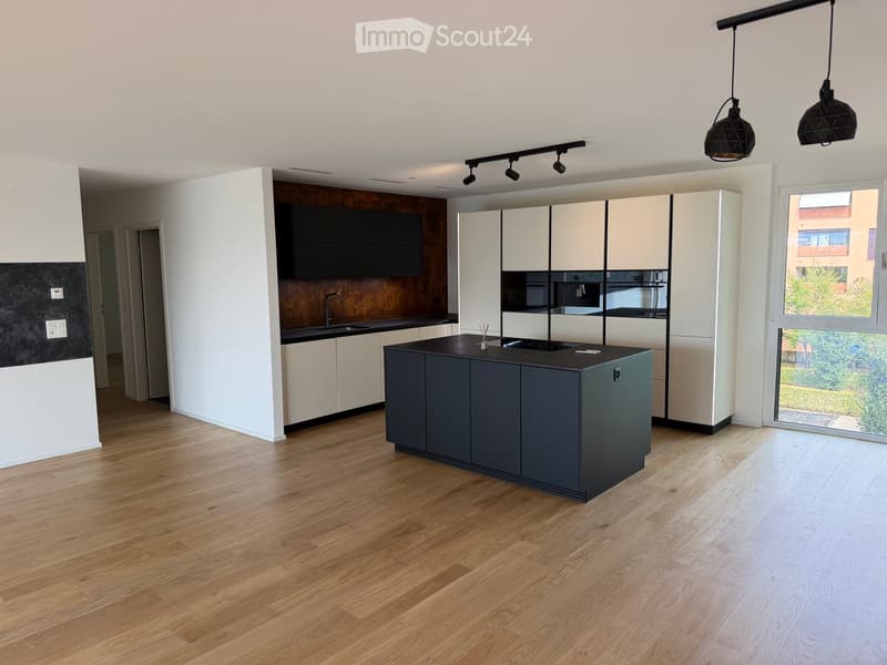 Modern kitchen with white and dark cabinets, a central island, and wooden flooring.