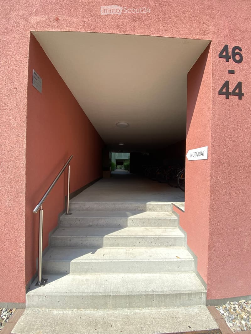 Other. {"visible_features": ["Raised ground floor"],    "type": "Building exterior",    "description": "Red building with concrete steps, stainless steel handrail, labeled '46-44', sign 'Notariat' at the entrance",    "localized_descriptions":