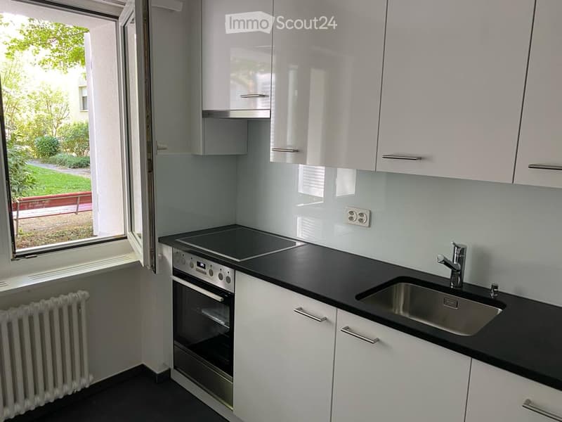 Modern kitchen with white cabinets, black countertops, built-in oven, and stainless steel sink.