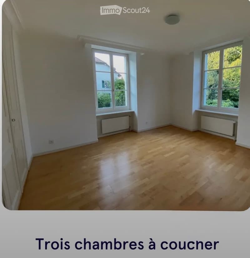 Empty room with wooden flooring, large windows, radiators, and white walls.