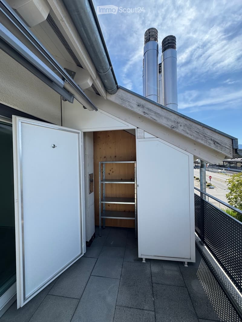 Balcony with tiled floor, white walls, metal railing, and two white cabinets with shelves.