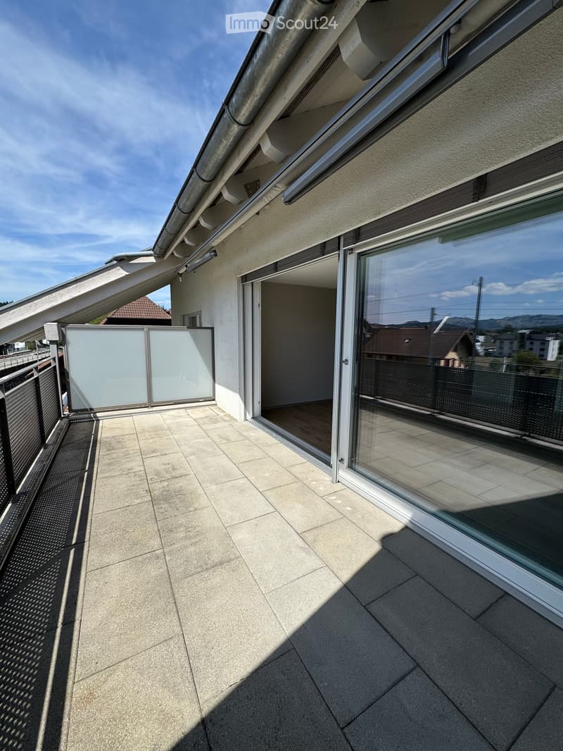 Balcony with tiled floor, glass sliding doors, and a view of the surrounding area.