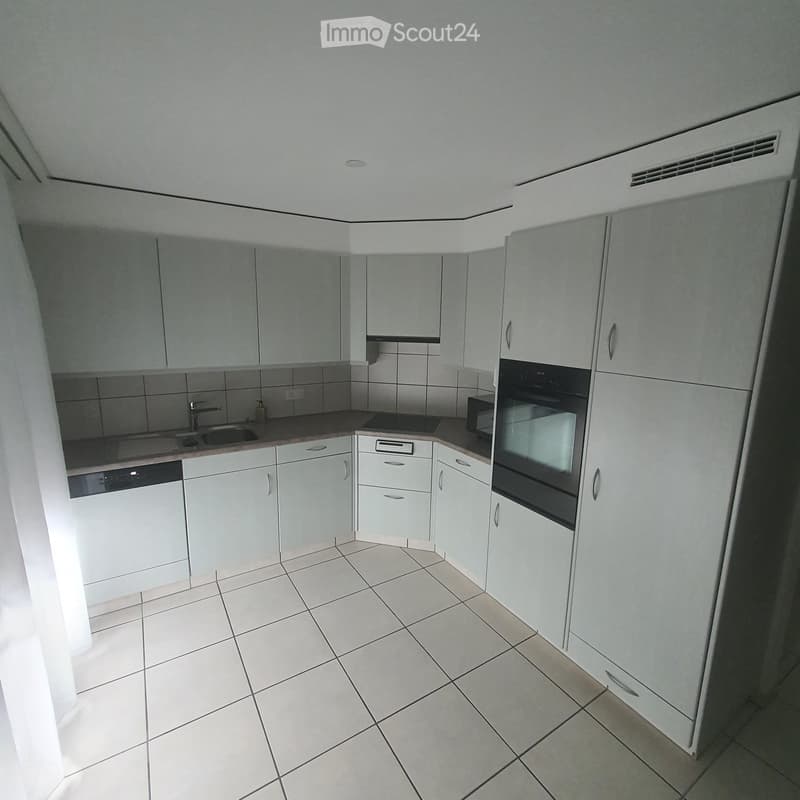 Modern kitchen with white cabinets, tiled floor, and stainless steel appliances including a sink, oven, microwave, and dishwasher.