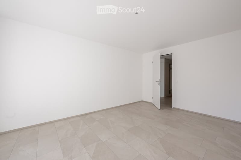 Empty room with white walls and tiled floor, featuring an open doorway leading to another space.