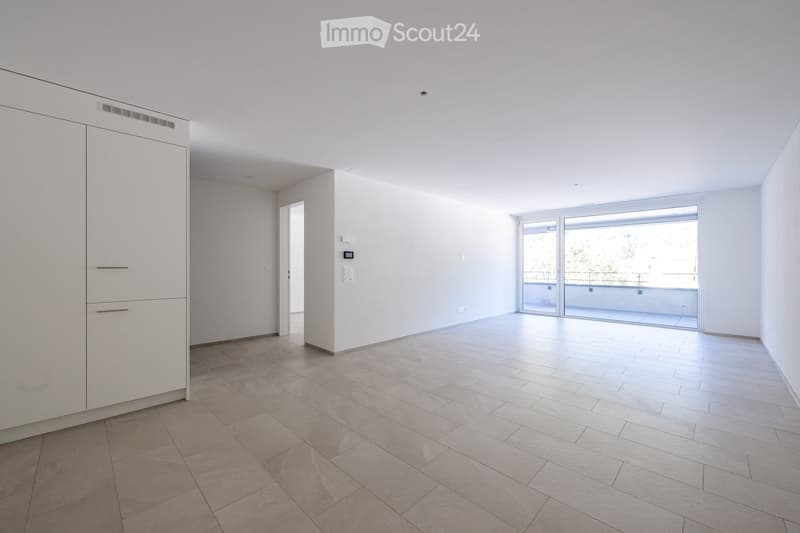 Empty room with white walls, tiled floor, and a sliding glass door leading to a balcony.