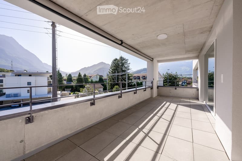 Modern balcony with tiled floor, metal railing, and expansive mountain view.