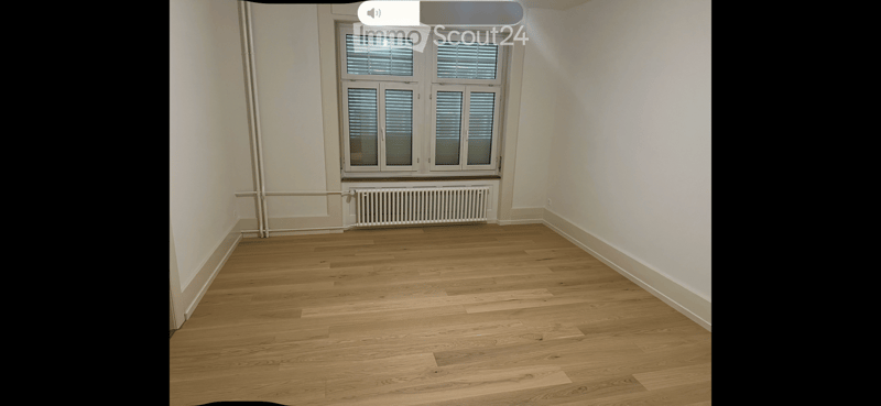 Empty room with wooden flooring, white walls, and a large window with blinds. No furniture or equipment is present.
