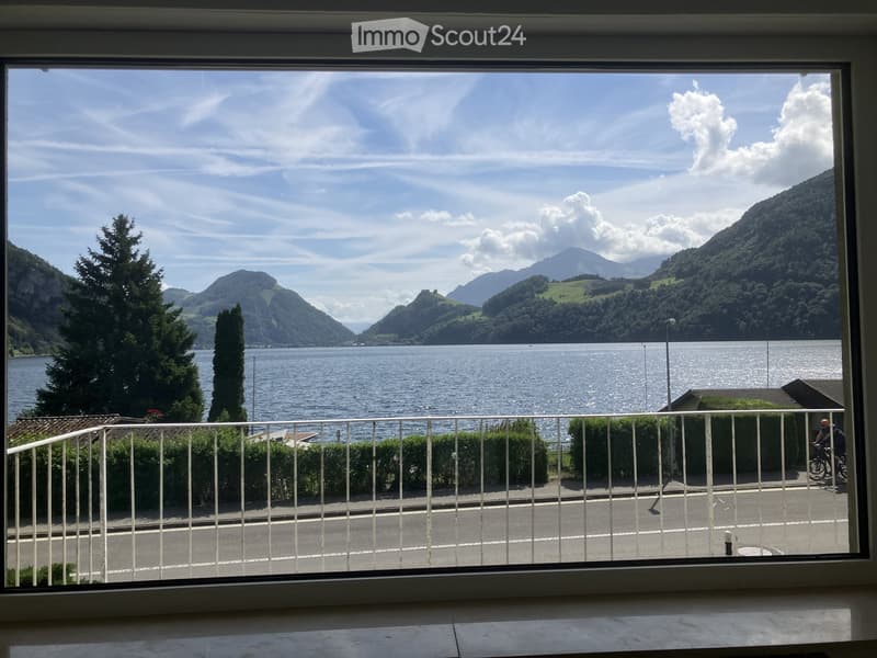 Balcony overlooking a scenic lake and mountain landscape with a road below.
