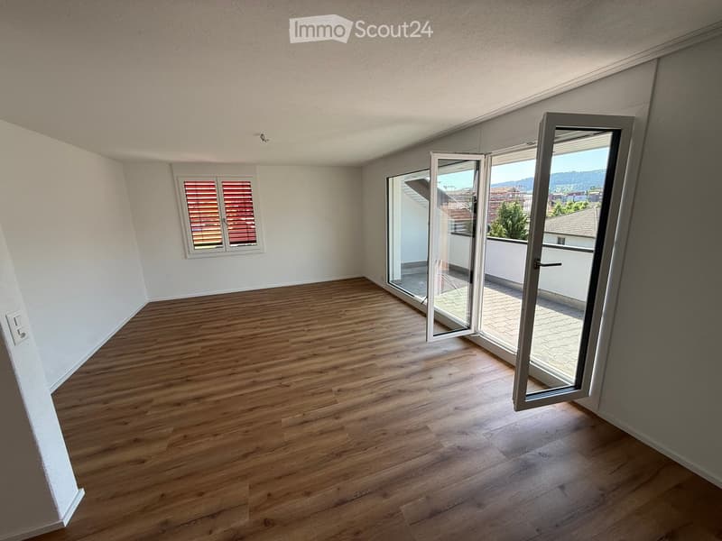 Empty room with wooden flooring, white walls, and large sliding glass doors leading to a balcony.