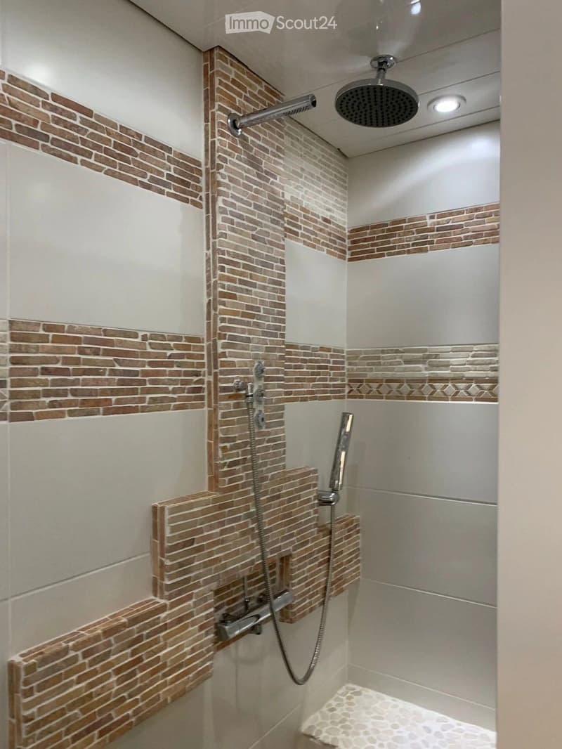 Modern shower area with brick and white tile accents, a handheld showerhead, and a built-in seat.