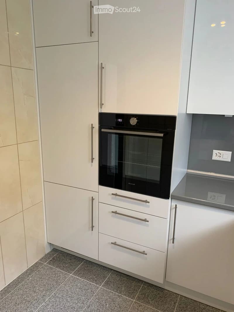 Modern kitchen with white cabinets, stainless steel handles, and a built-in oven.